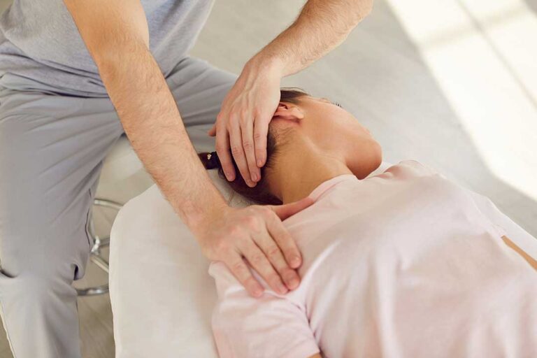 Person using a heating pad on the lower back while seated with one leg extended gently.