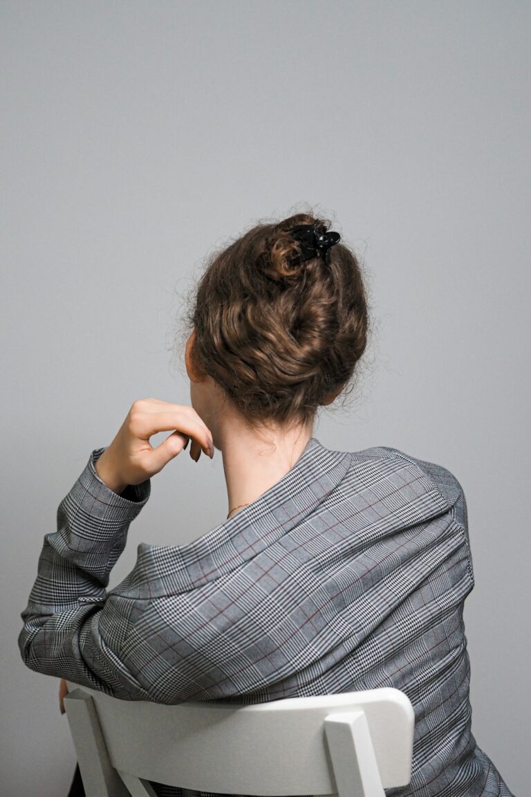 Person seated at a desk gently tilting the head during a neck stretch with relaxed shoulders.
