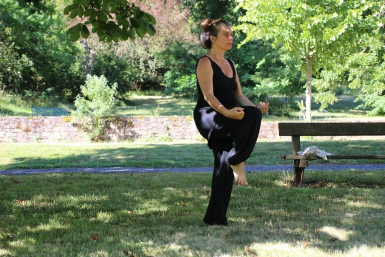 Adult performing a controlled core exercise on a mat beside a supportive chair.